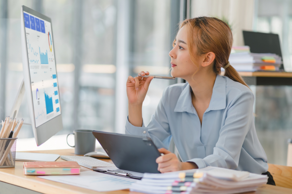 Woman in light blue button down shirt working on a tablet at a desk